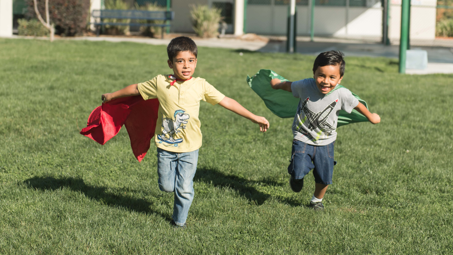 Two young student wearing capes and running
