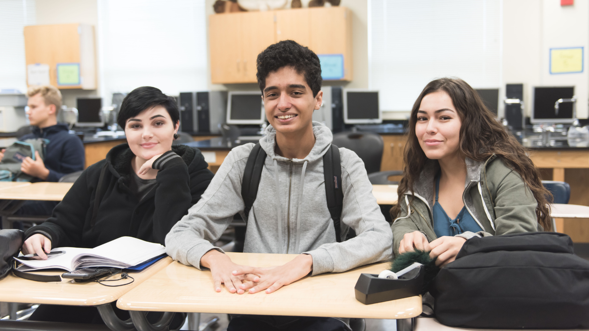 Three high schools students sitting at table working on project.